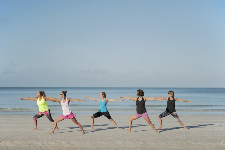 Woman doing boat yoga pose on the beach